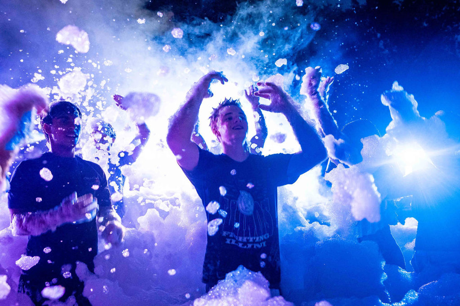Guests under blue lights at a nighttime foam event